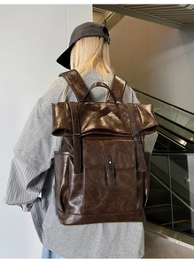 Side view of a vintage dark brown leather backpack being worn by a person in a mall