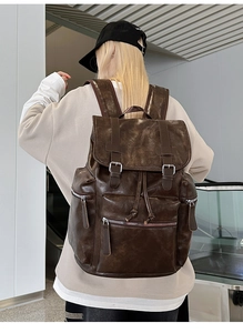 Detail of vintage brown PU leather backpack showing silver buckles and zipper pockets