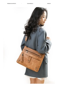 Detailed side view of vintage washed leather crossbody bag with fringe and multiple zippers