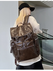 Detail view of a vintage dark brown leather backpack with buckle closure on male model