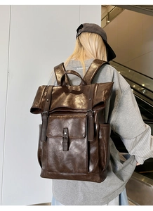 Detail of dark brown vintage PU leather backpack with buckle straps and flap pockets