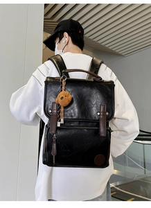 Detailed view of black PU leather backpack with vintage straps and plush bear charm