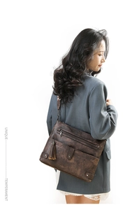 Close-up of vintage brown washed leather crossbody bag with multiple zippers and tassels