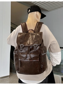Detail of dark brown vintage leather backpack with front pockets and buckle closure