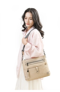 Detail of beige washed leather crossbody bag with geometric strap and tassel decoration