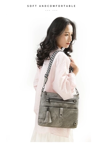 Side view of gray washed leather crossbody bag with multiple zippers and woven strap