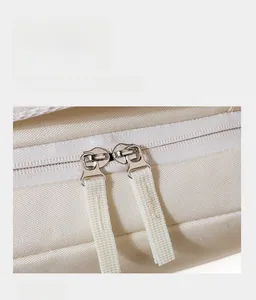 Macro detail of smooth two-way zippers with durable webbing pullers on a cream backpack