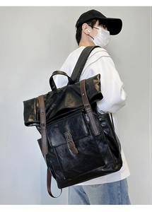 Detail of vintage black PU leather roll-top backpack with brown strap and magnetic buckle