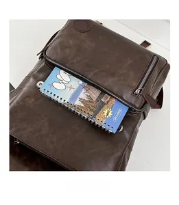 Detailed view of dark brown faux leather backpack front pocket with zipper and notebook