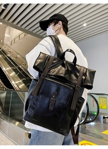 Side view of large vintage black PU leather backpack with brown straps and metal buckles