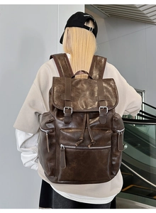 Rear view of model wearing a vintage dark brown leather backpack in a modern mall setting