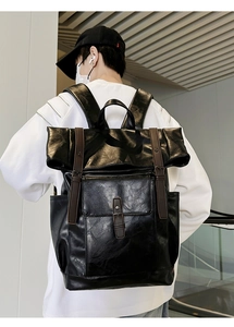 Rear view of model wearing a large vintage black PU leather backpack with brown straps