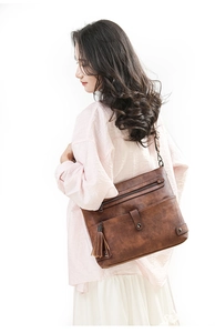 Detail view of vintage caramel shoulder bag with washed leather texture and tassel