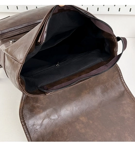 Detail view of the soft PU leather backpack interior showing black fabric lining and zipper pocket