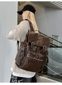 Close-up of vintage brown PU leather backpack featuring rustic texture and twin buckle straps