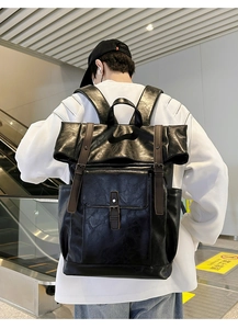 Detailed view of black PU leather roll-top backpack with brown straps and buckle