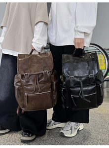 Detail view of brown and black PU leather backpacks with drawstring and buckle closure