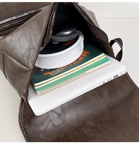 Detail view of large capacity dark brown PU leather backpack with laptop and headphones
