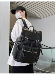Side view of a large black vintage PU leather backpack with buckle straps and side zippers