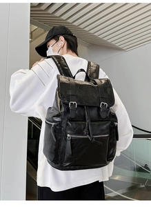Rear view of large black leather backpack showing buckles and side pocket details