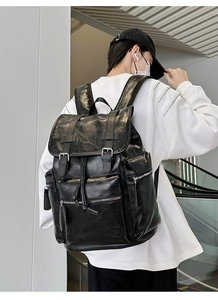 Close-up of black leather backpack with dual buckle straps and soft texture detail
