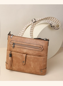 Close-up of vintage faux leather crossbody bag with fringe detail and woven strap