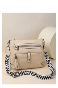 Detail of beige crossbody bag featuring woven geometric strap and stylish leather tassels
