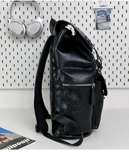 Detail of black PU leather backpack showing side zipper pocket and premium texture