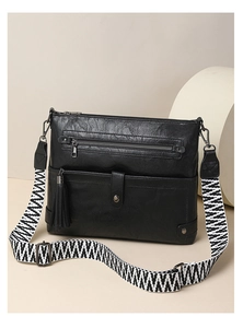 Close-up of black washed leather crossbody bag with geometric pattern wide strap