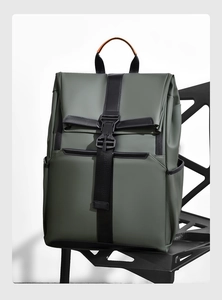Detail of army green travel backpack with black buckles on minimalist black chair