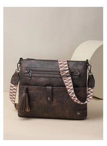 Detail of dark brown vintage crossbody bag with ethnic patterned strap and leather tassel