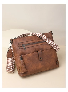 Close-up of vintage brown leather handbag with patterned woven strap and fringe details