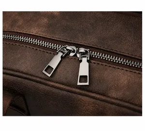 Detail of smooth double metal zipper and vintage brown leather texture on a backpack