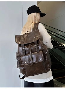 Detail of vintage brown PU backpack with fold-over flap and buckle on a model