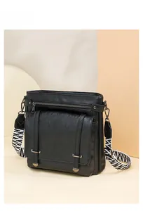 Detail of multi-pocket black bucket bag with a stylish geometric patterned wide strap