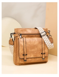 Detail of vintage brown crossbody bucket bag with geometric woven strap and silver hardware