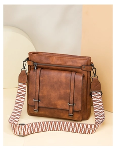 Detail of vintage brown leather crossbody bag with geometric woven strap and flap pocket