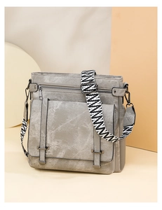 Detail of grey canvas crossbody bag featuring wide geometric strap and front buckle pocket