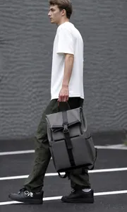 Detail of dark grey waterproof backpack with roll-top closure and orange handle accent