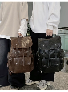 Detail of vintage PU leather backpacks showing drawstring closures and metal rivet buckles