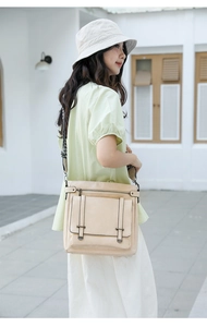 Close-up of beige bucket bag with front flap pocket and wide fabric shoulder strap