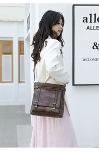 Detail of vintage dark brown crossbody bucket bag with flap cover and metallic buckles