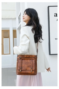 Brown vintage leather shoulder bag with buckle detail and woven strap on female model
