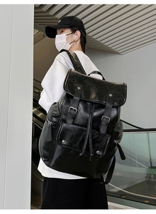 Detailed view of black PU leather backpack with silver buckles and large front pocket
