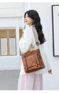 Detail of vintage brown bucket bag with wide woven strap and double buckle flap pockets