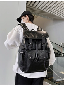 Detail of black PU leather backpack showing fine texture and silver hardware on a male model