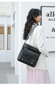 Detail of black matte PU leather bucket bag featuring a wide geometric woven shoulder strap
