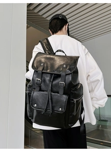 Detailed view of black PU leather backpack with silver buckles worn by a model in a modern room