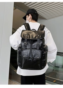 Rear view of a black PU leather backpack with buckle straps worn in a modern interior