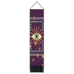 Detail of bohemian evil eye tapestry with wooden rod, purple base and black tassel fringe